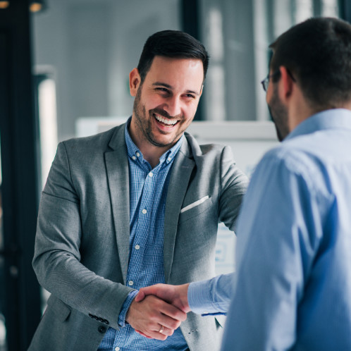 a man in a suit smiling and shaking hands with another man