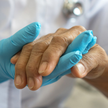 a person's hand in a blue glove holding another hand